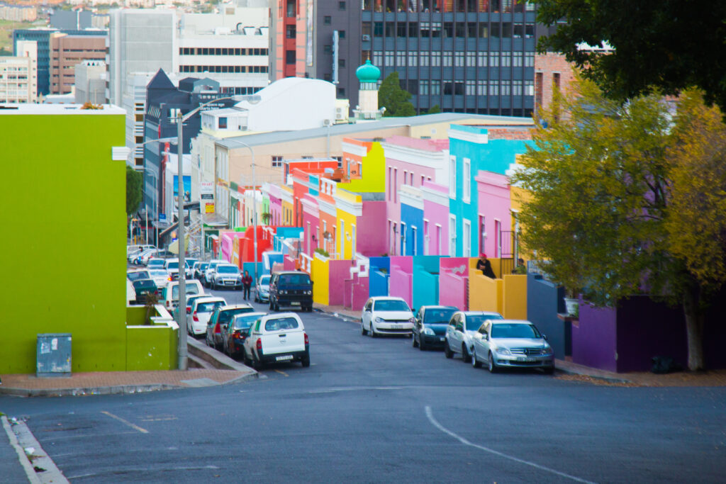 Vibrant Bo-Kaap street in Cape Town with rows of brightly painted houses in green, pink, blue, and yellow.”